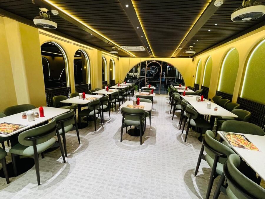 Arched alcoves and olive-green seating inside a Drizzl's Pizza outlet
